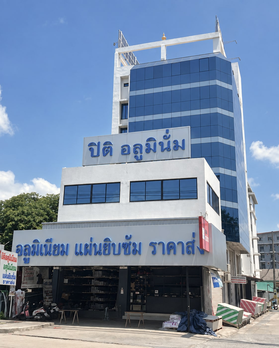 อาคารบริษัท ปิติ อลูมินั่ม จำกัด ริมถนนรัตนาธิเบศร์ ตึกกระจกสีน้ำเงิน ป้ายชื่อร้านอยู่ชั้นบน ป้ายอลูมิเนียม แผ่นยิบซั่ม ราคาส่ง อยู่เหนือหน้าร้าน